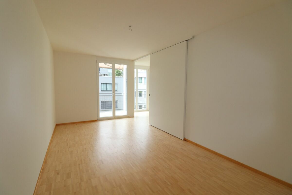 Heller leerer Wohnraum mit Schiebetür und Balkonblick