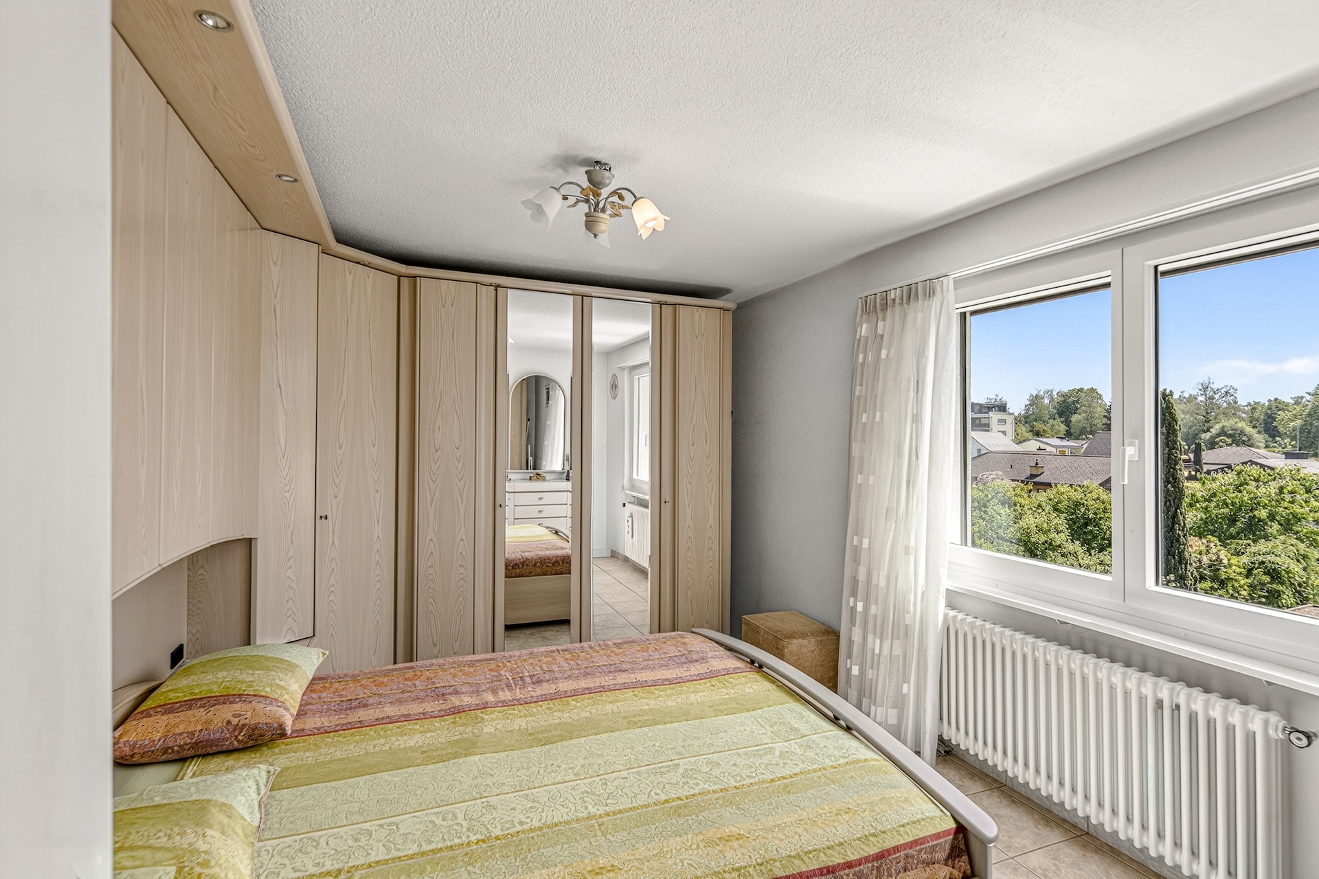 Helles Schlafzimmer mit Einbauschrank und Blick ins Grüne