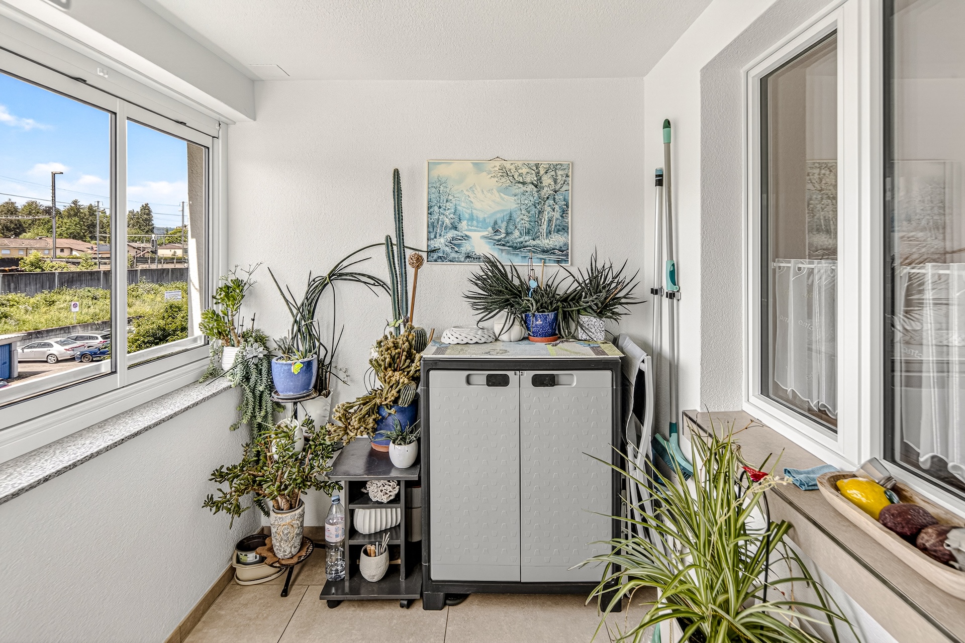 Verglaster Balkon mit Pflanzen und Abstellschrank