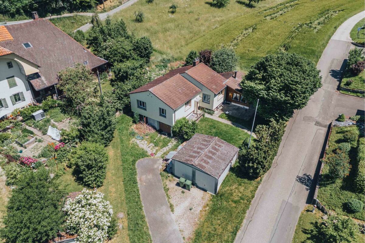 Luftaufnahme eines Einfamilienhauses mit Nebengebäude und Garten