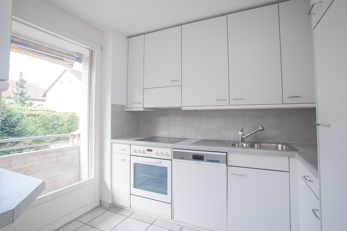 Helle weiße Küchenzeile mit Fenster zum Balkon