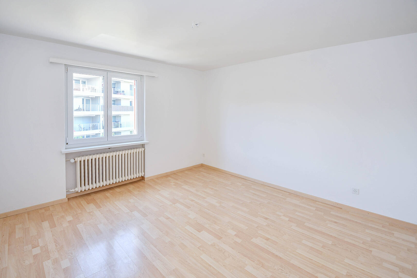 Leerer, heller Wohnraum mit Fenster und Heizkörper