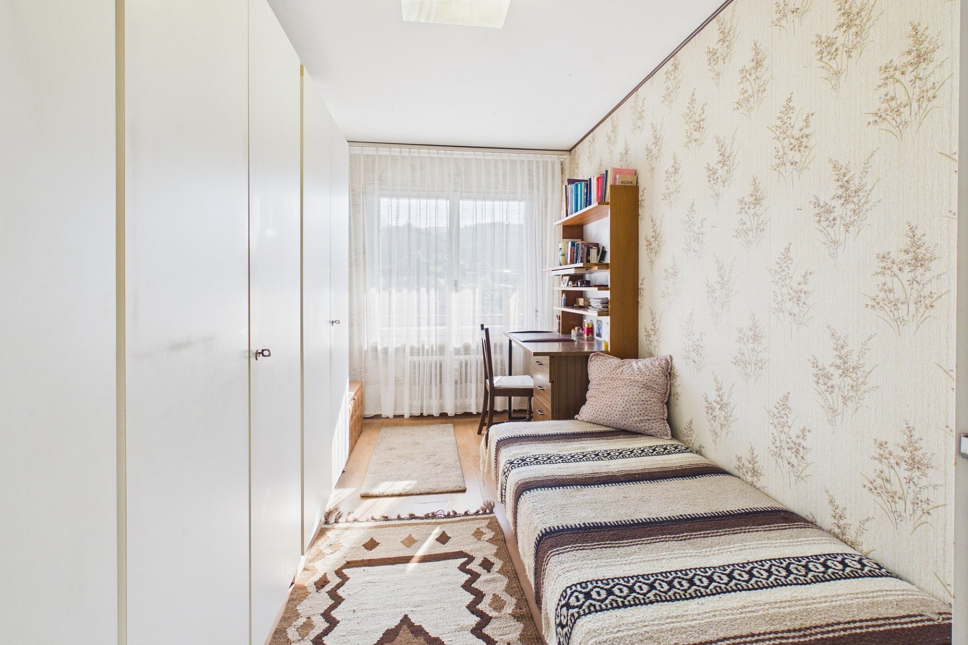 Schmaler Wohnraum mit Bett und Arbeitsplatz