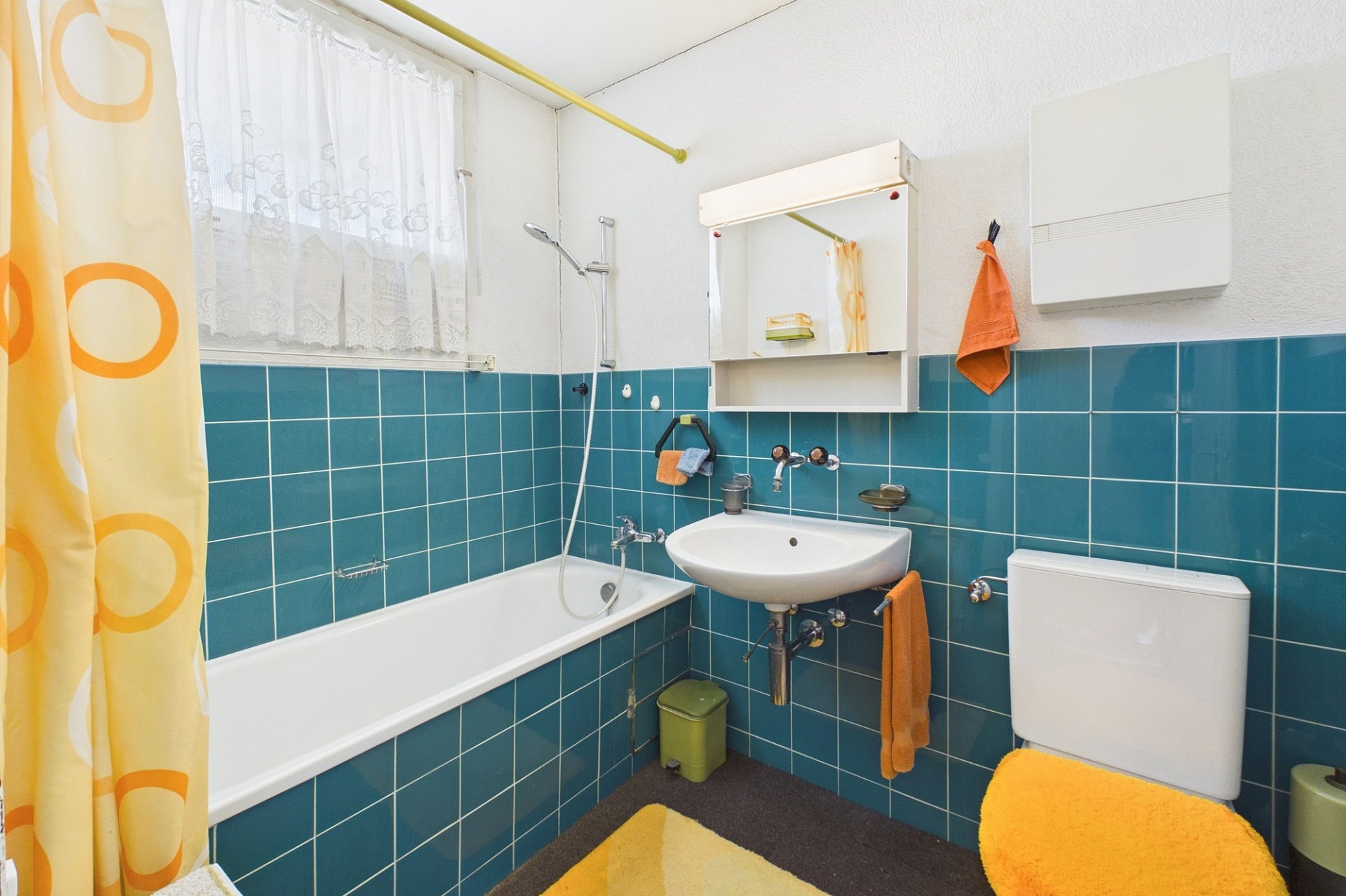 Kleines Badezimmer mit Badewanne und türkisfarbenen Fliesen