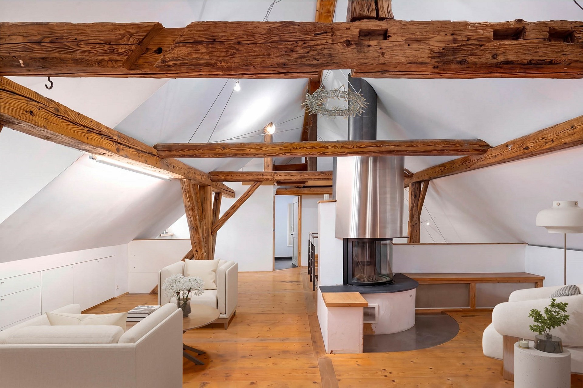Offener Wohnraum mit sichtbaren Holzbalken und Kamin