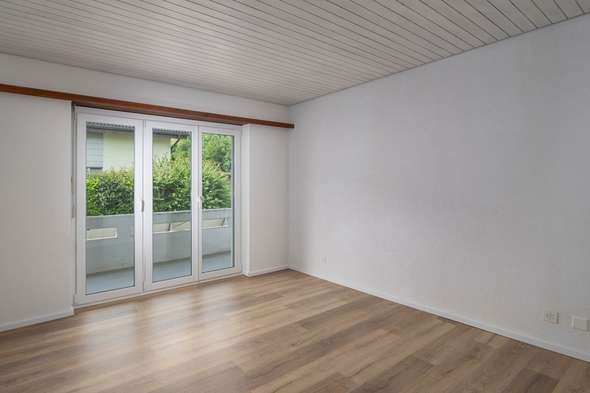 Leerer Wohnraum mit Balkonzugang