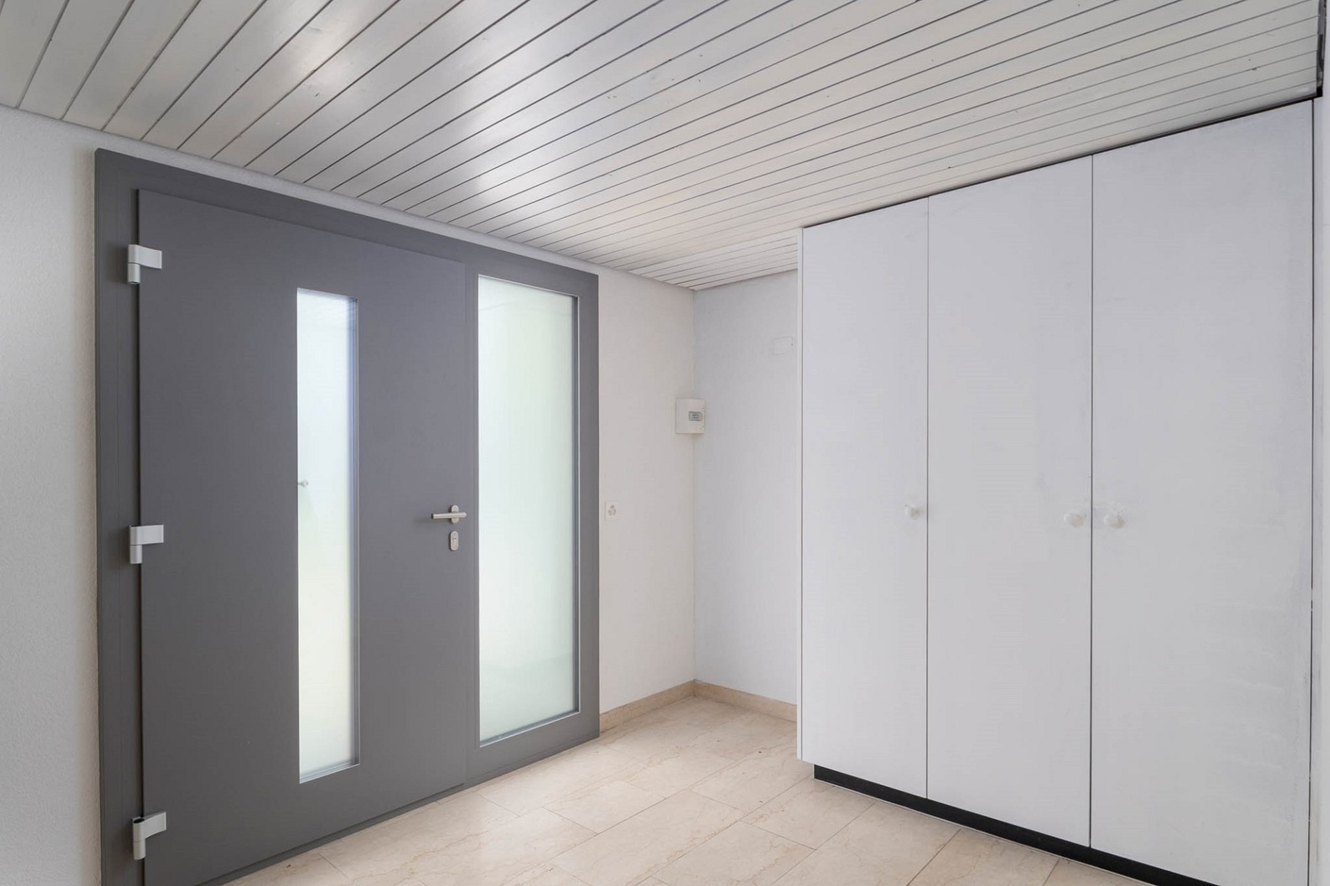 Moderner Eingangsbereich mit grauer Haustür und Einbauschrank
