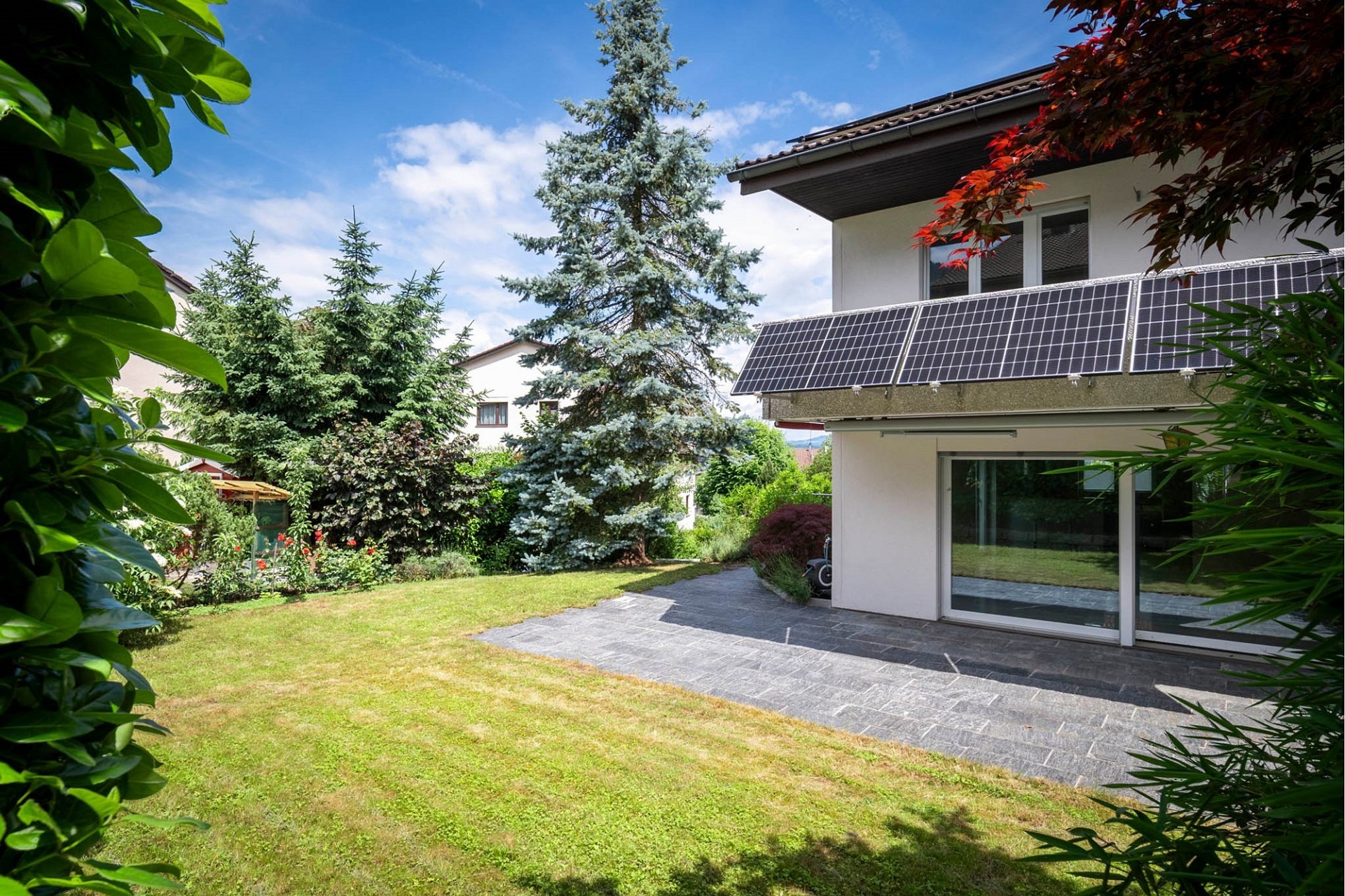 Gartenansicht mit Balkon und Solarmodulen