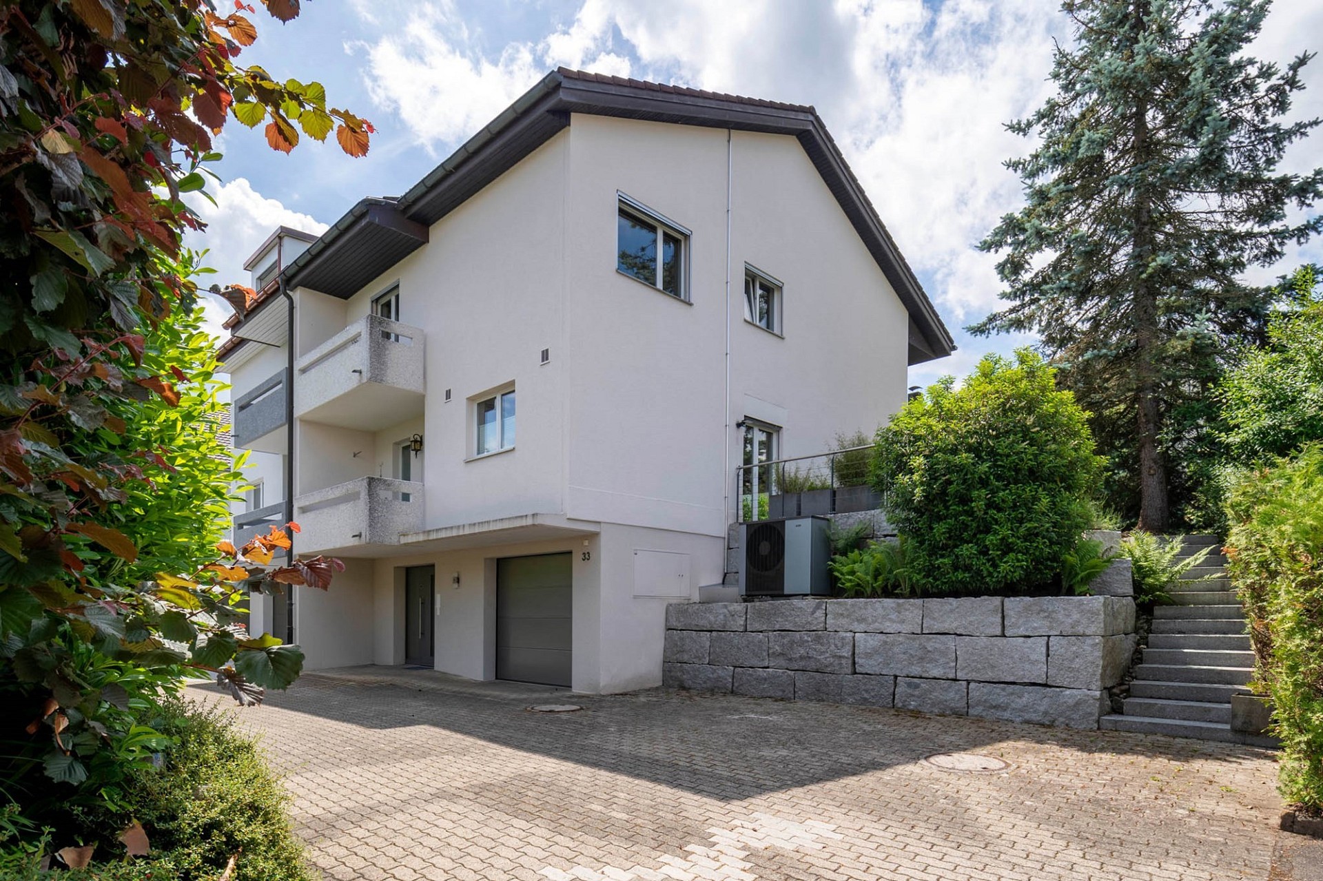 Außenansicht eines modernen Wohnhauses mit Einfahrt und Gartenanlage