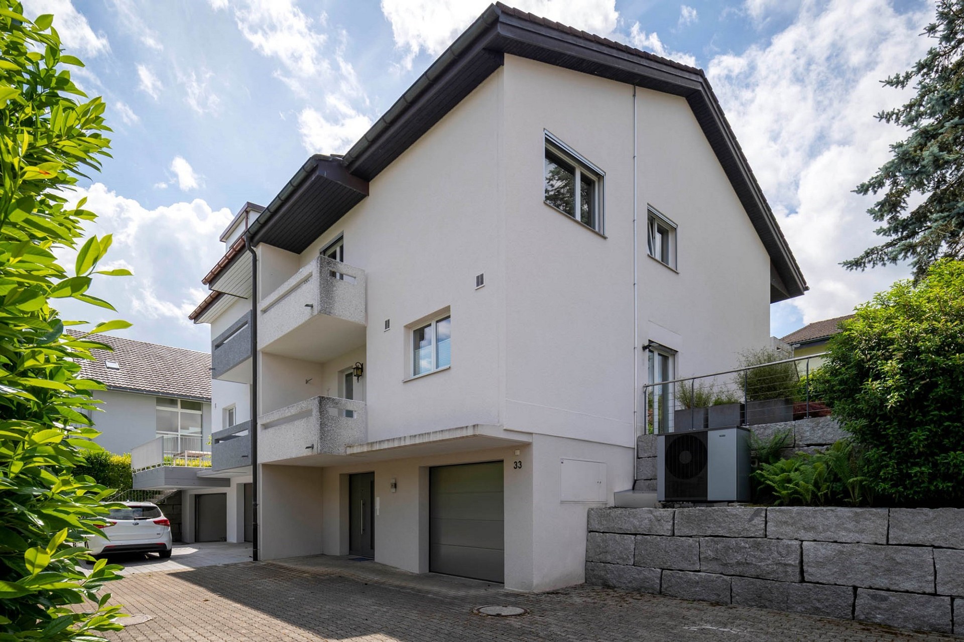 Außenansicht eines modernen Mehrfamilienhauses mit Garagen und Balkon