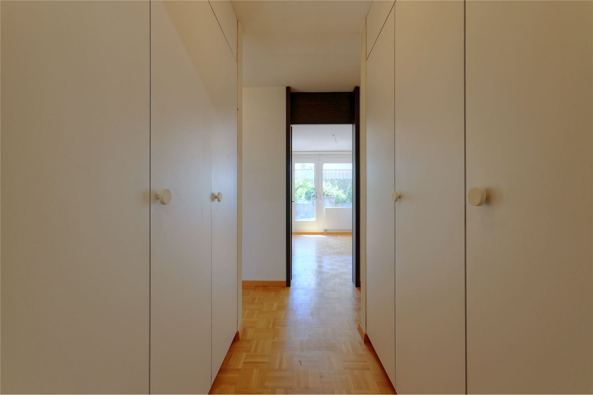 Flur mit Einbauschränken und Blick in einen hellen Raum