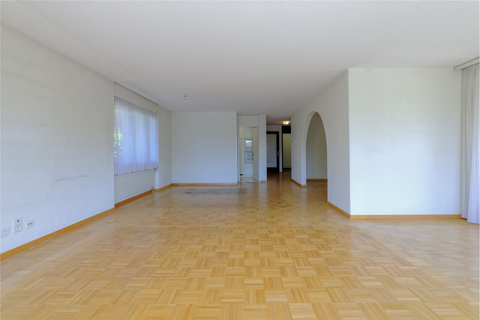 Großer leerer Wohnraum mit Parkettboden
