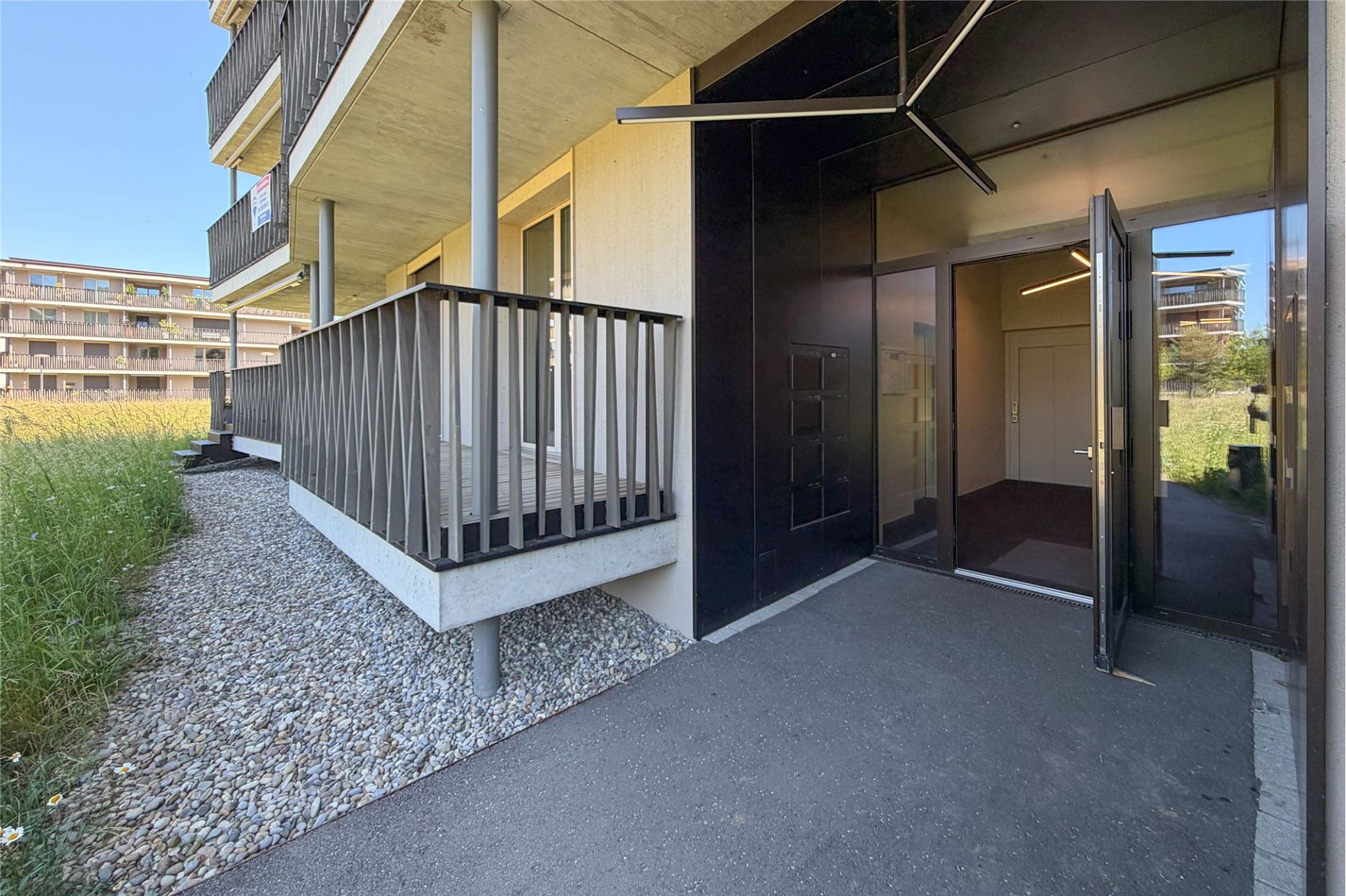 Außenansicht eines modernen Wohngebäudes mit Balkon und Eingang