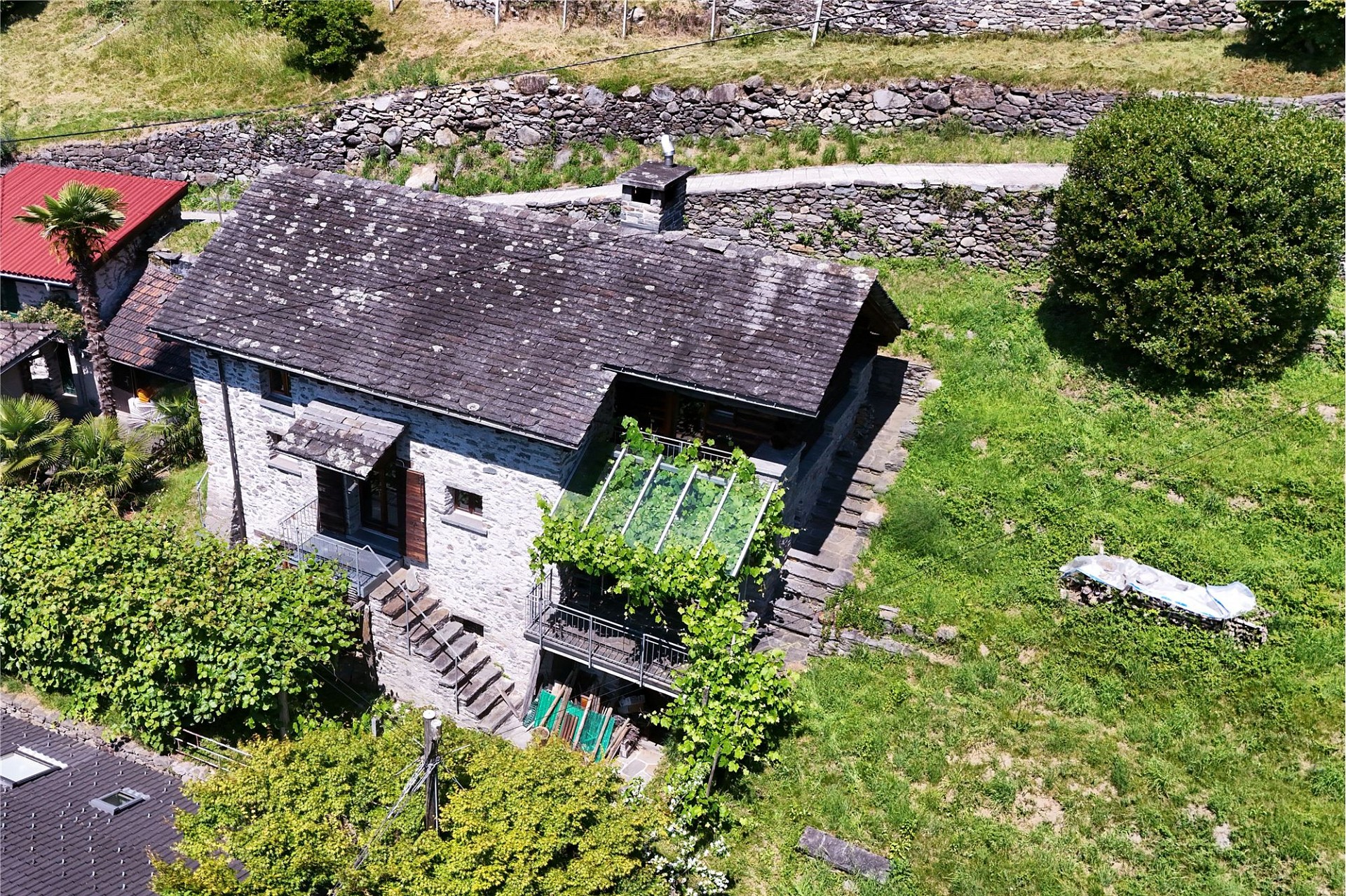 Steinhaus mit steilem Schieferdach im Grünen