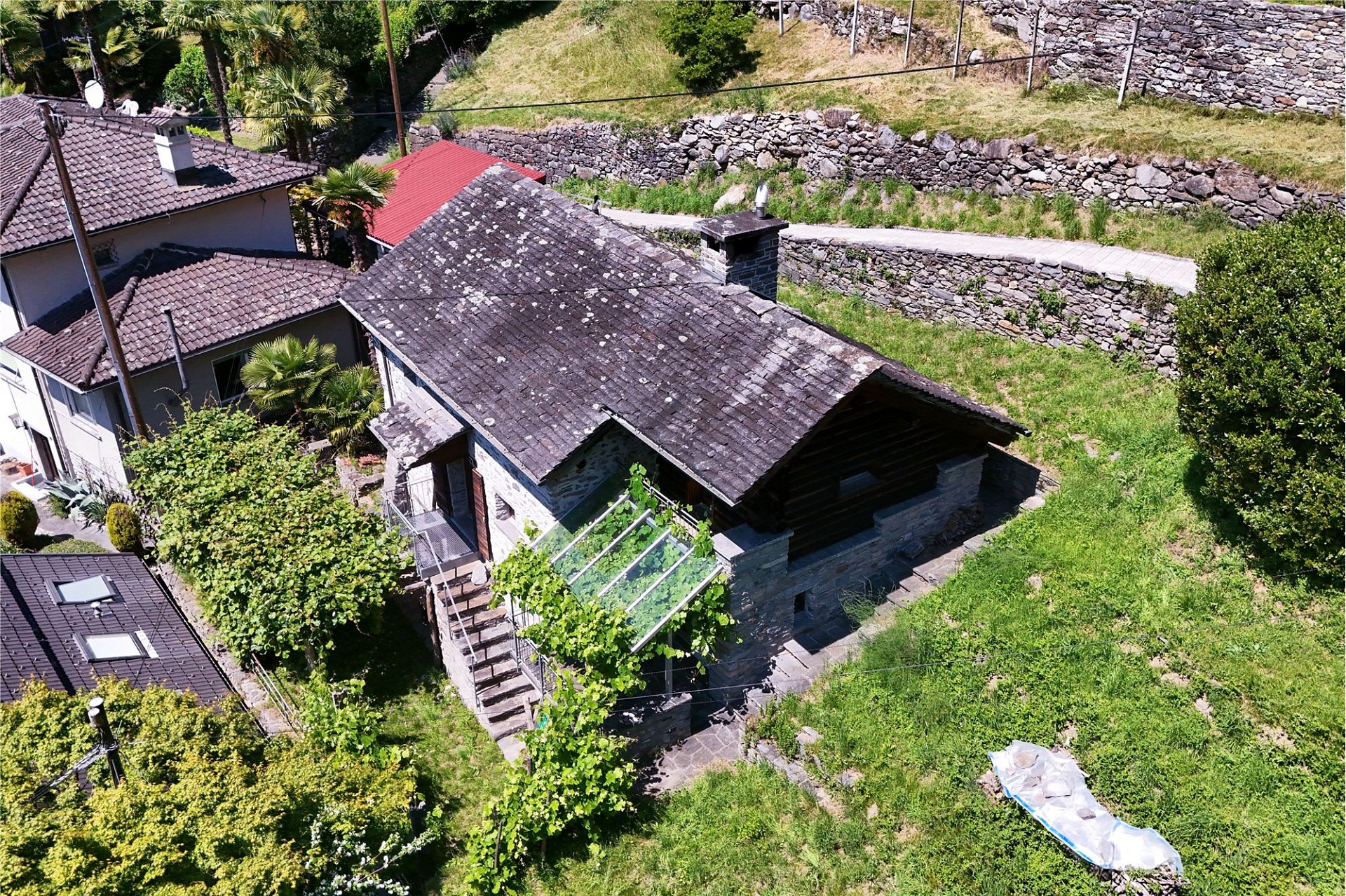 Luftaufnahme eines Hauses mit Garten und umliegenden Steinmauern