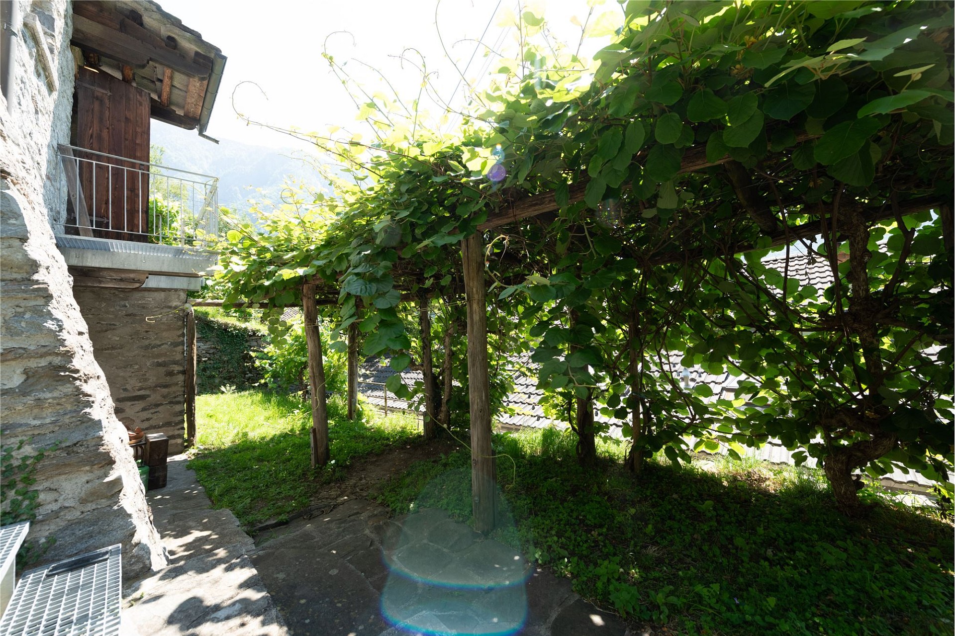 Bewachsener Außenbereich mit Naturstein und Holzpergola