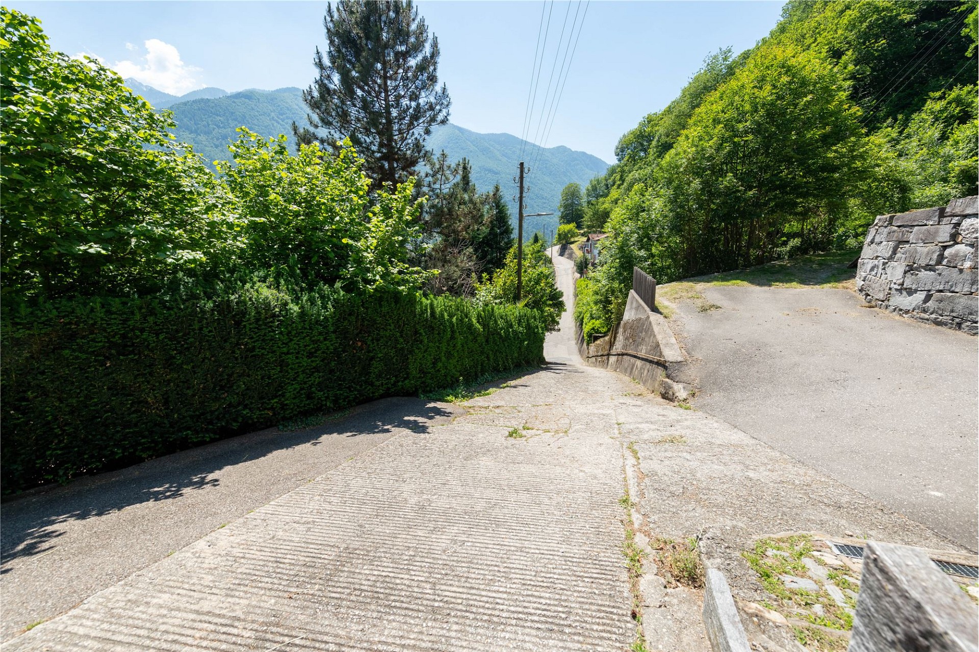 Steile Zufahrtsstraße in grüner Berglandschaft