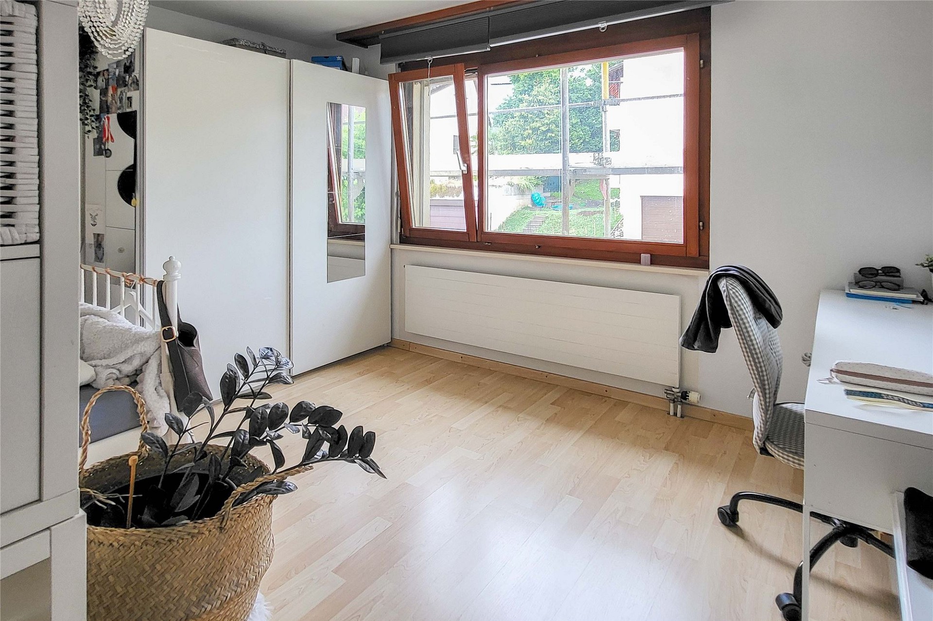 Helles Schlafzimmer mit großem Fenster und Kleiderschrank