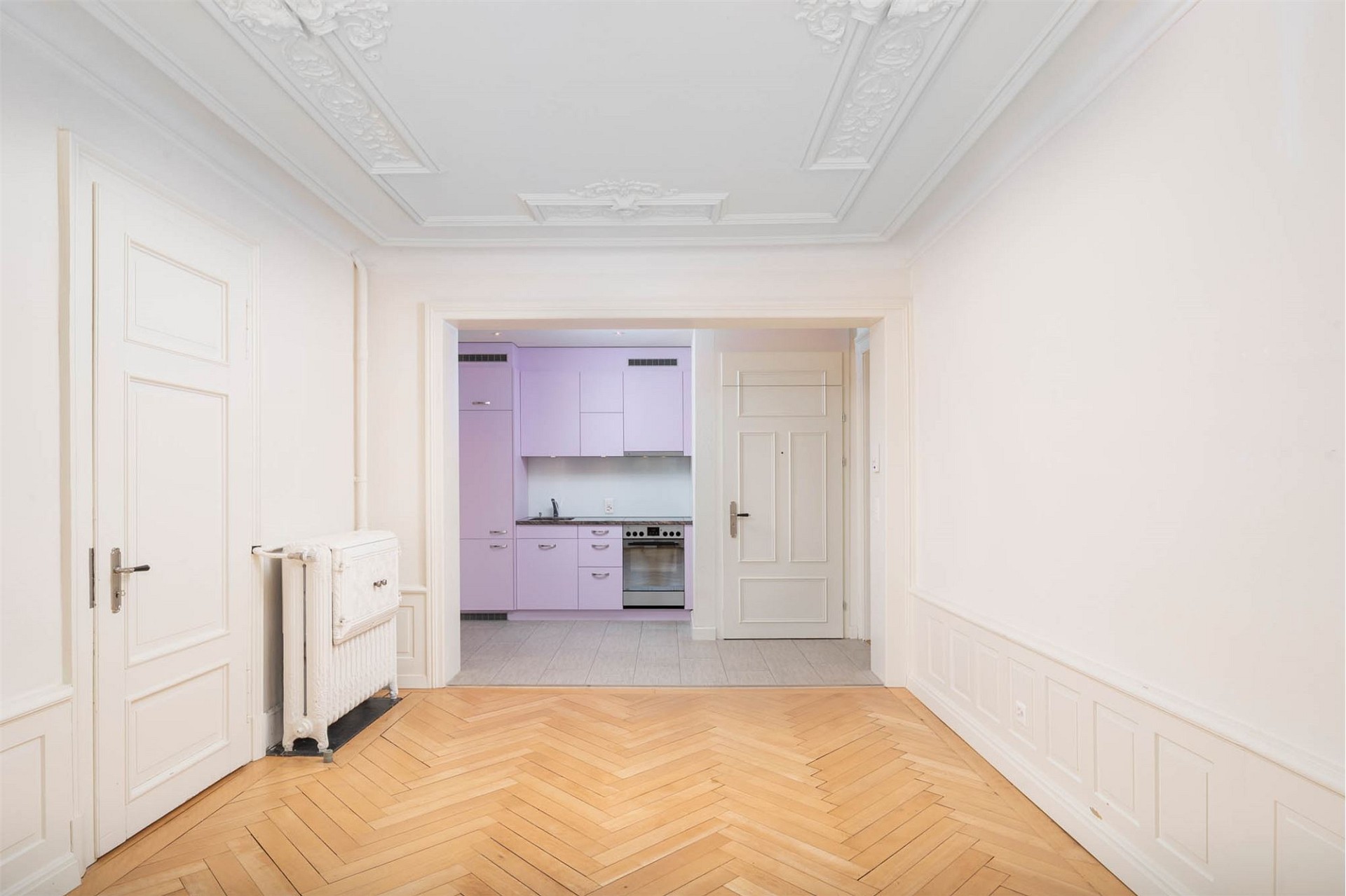 Eleganter Altbau-Flur mit Blick in eine lilafarbene Küche