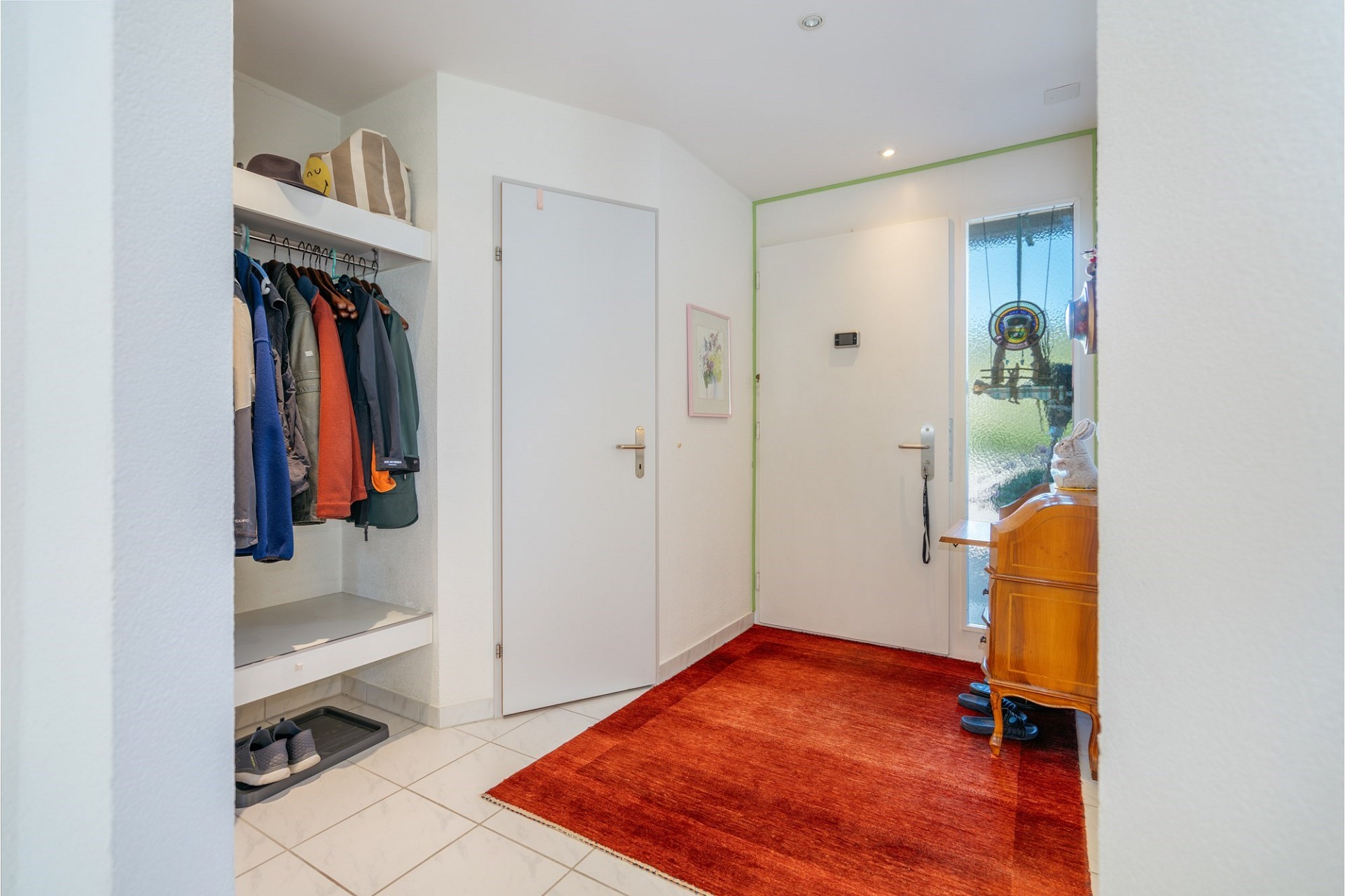 Heller Eingangsbereich mit Garderobe und rotem Teppich