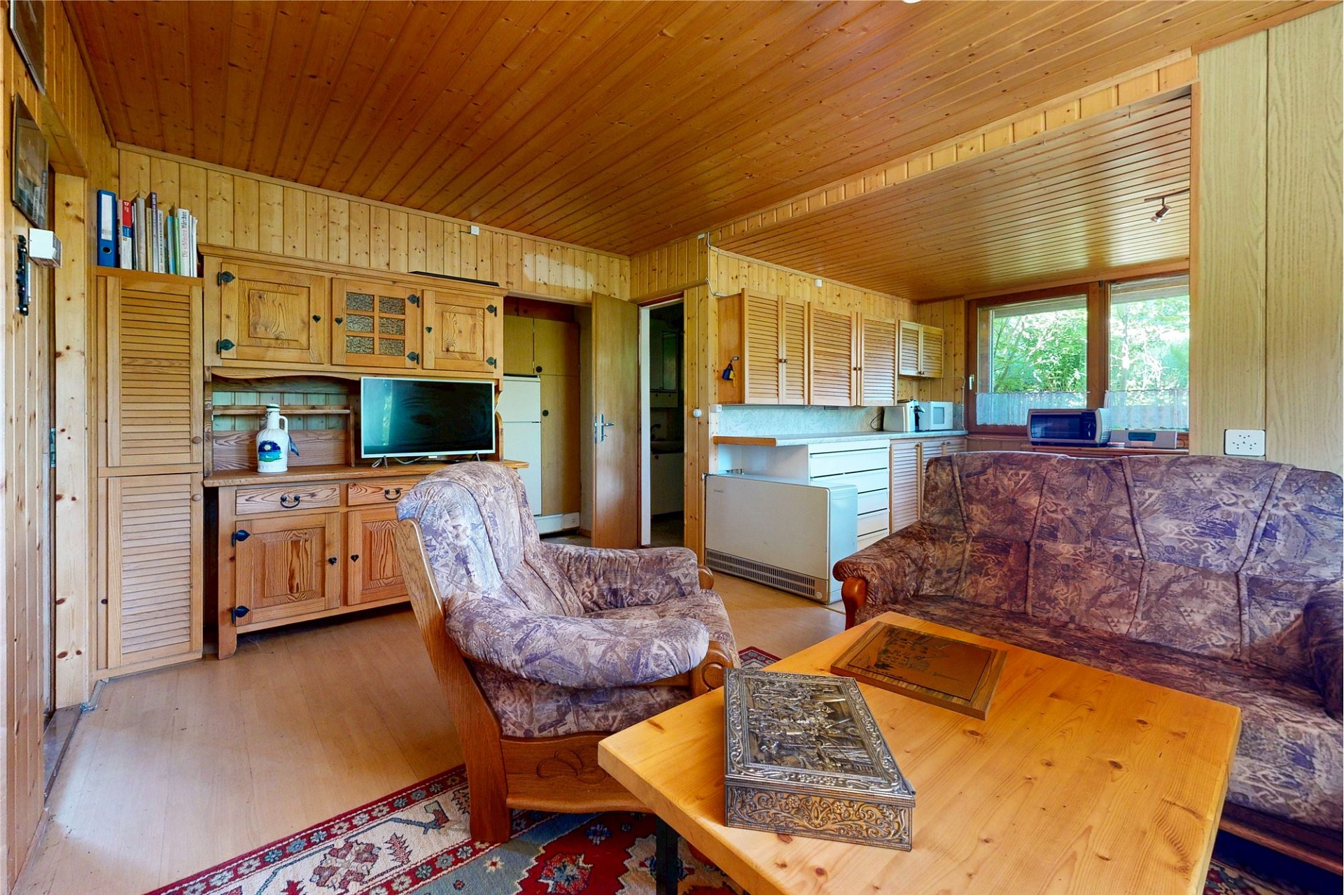Gemütliches Holz-Wohnzimmer mit offener kleiner Küche