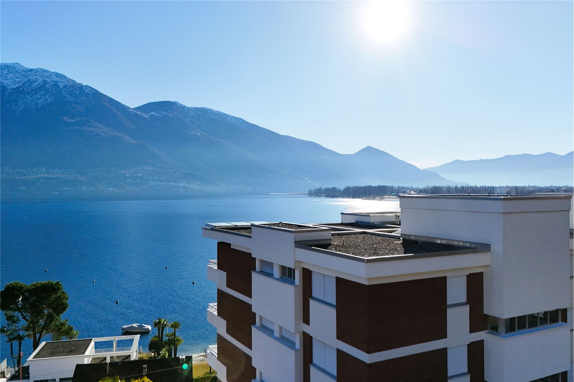 Blick auf See und Berge mit modernem Gebäude im Vordergrund