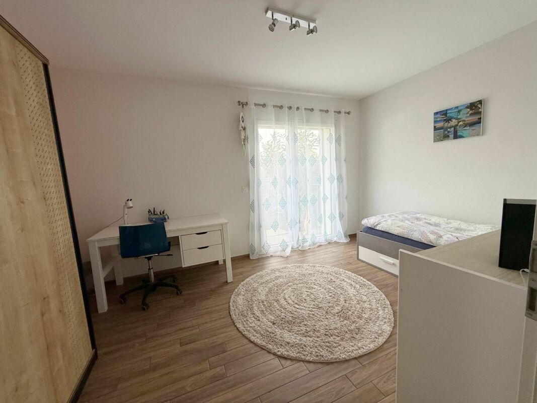 Helles Schlafzimmer mit Schreibtisch und Einzelbett