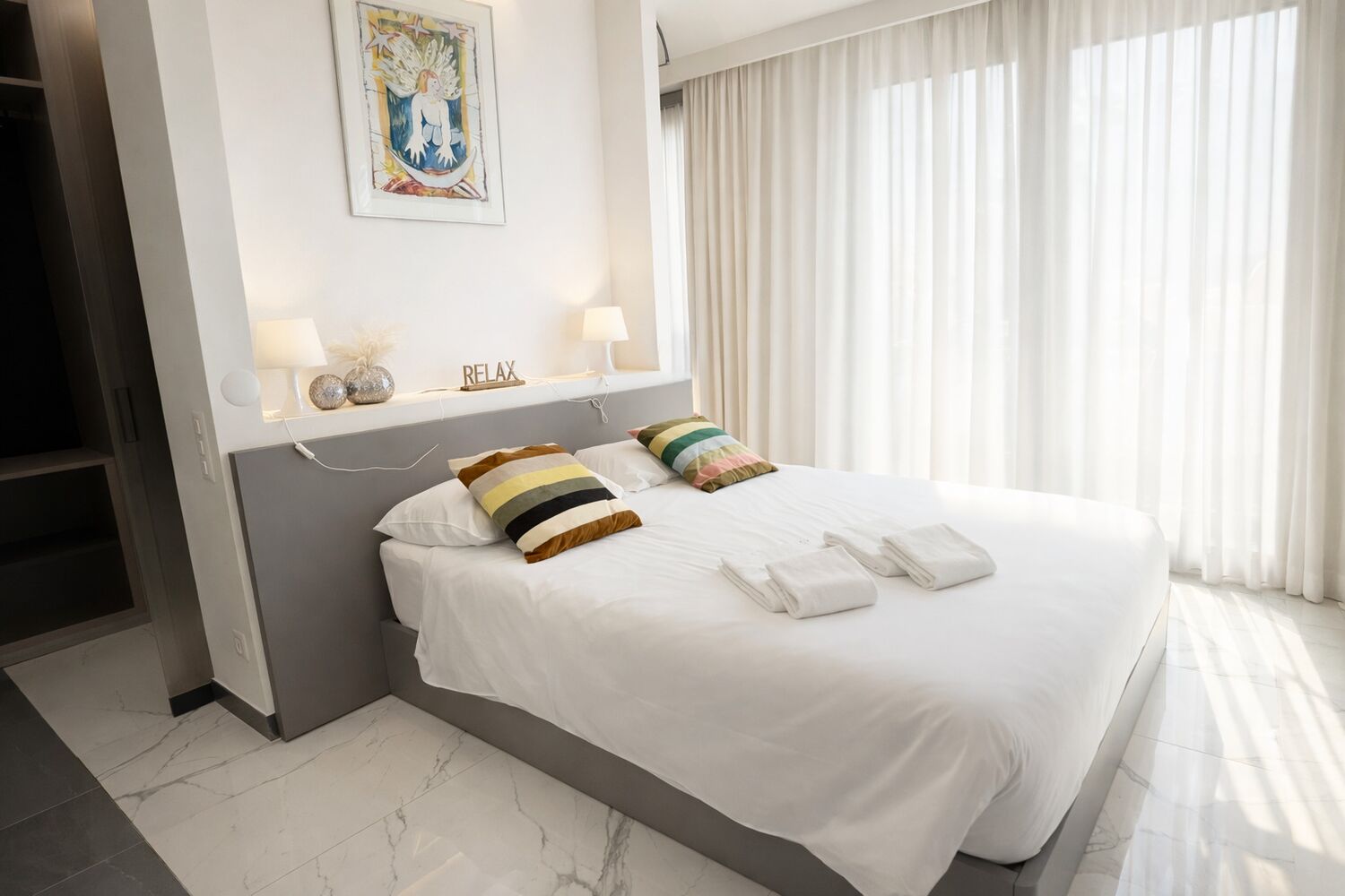 Helles Schlafzimmer mit großem Bett und Vorhängen