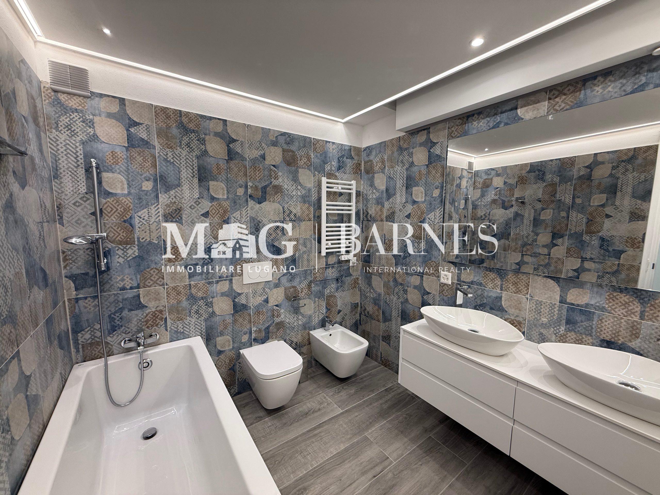 Modernes Badezimmer mit Badewanne, Doppelwaschtisch und Mosaikfliesen