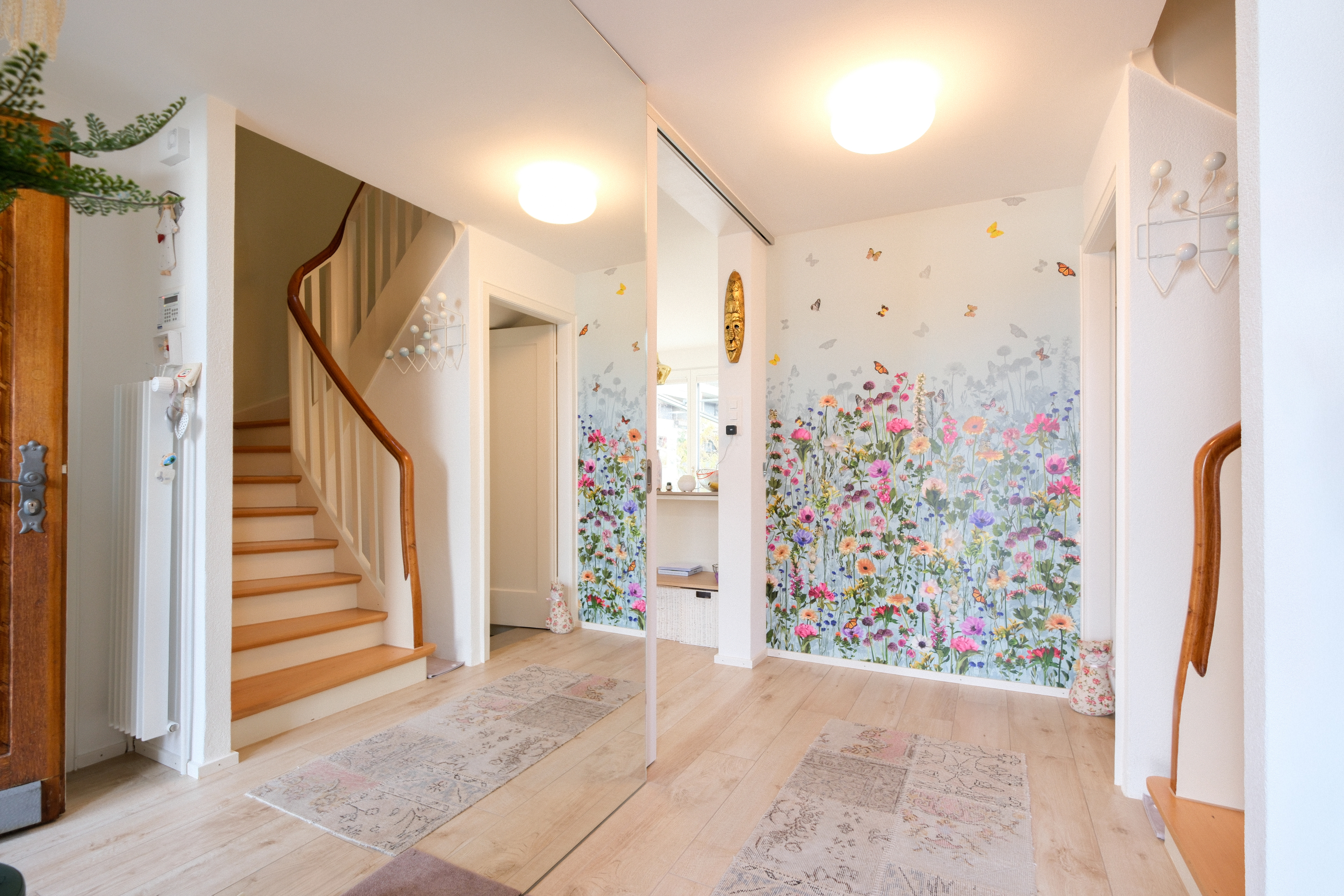 Heller Eingangsflur mit Treppe und Spiegelwand