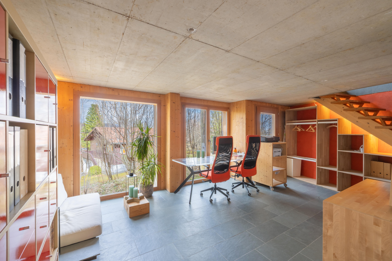 Arbeitszimmer mit großen Fenstern und offener Holztreppe