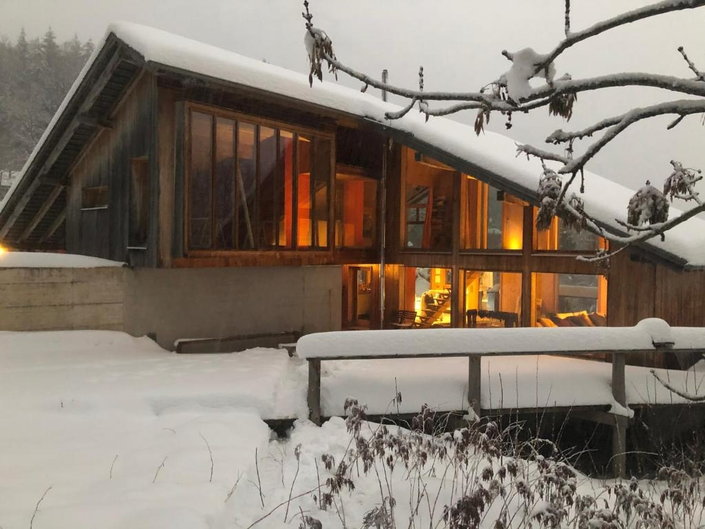Verschneites Holzhaus mit großen Glasflächen