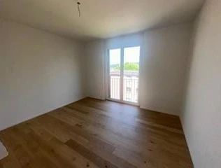 Leerer heller Raum mit Holzboden und Balkontür