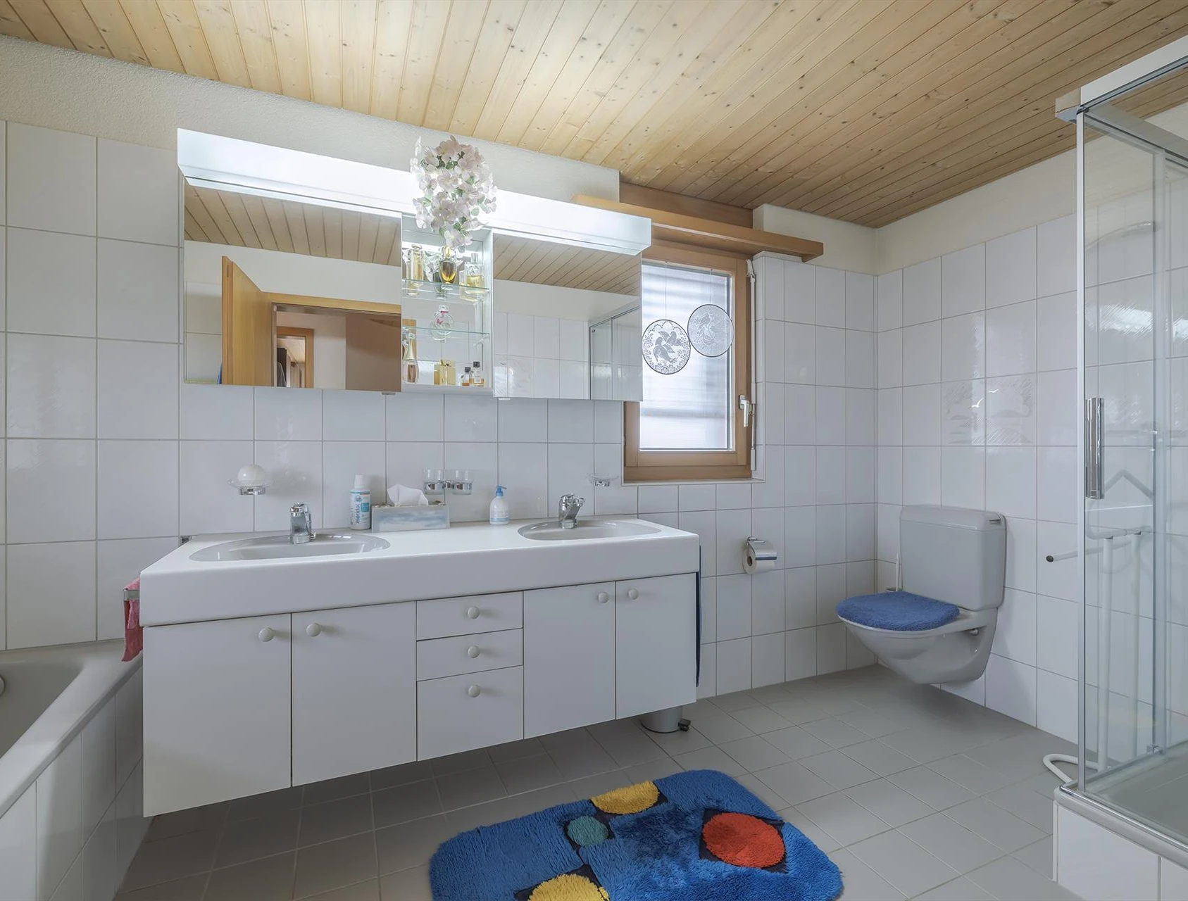 Helles Badezimmer mit Doppelwaschtisch, WC und Dusche