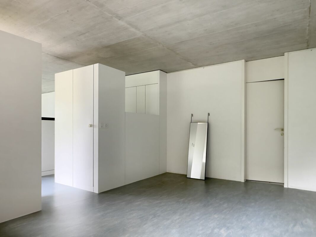 Minimalistischer Innenraum mit Beton-Decke und weißen Einbauten