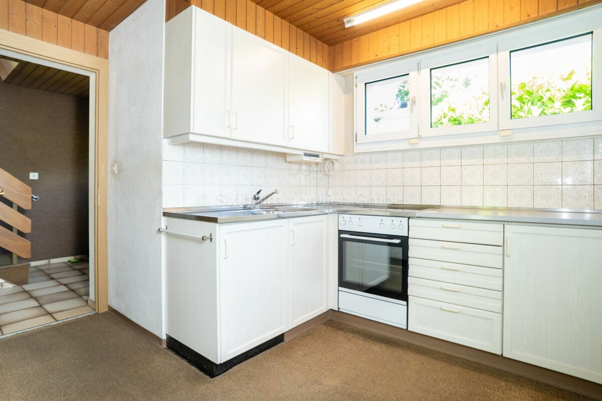 Helle Küche mit weißen Schränken und Holzdecke
