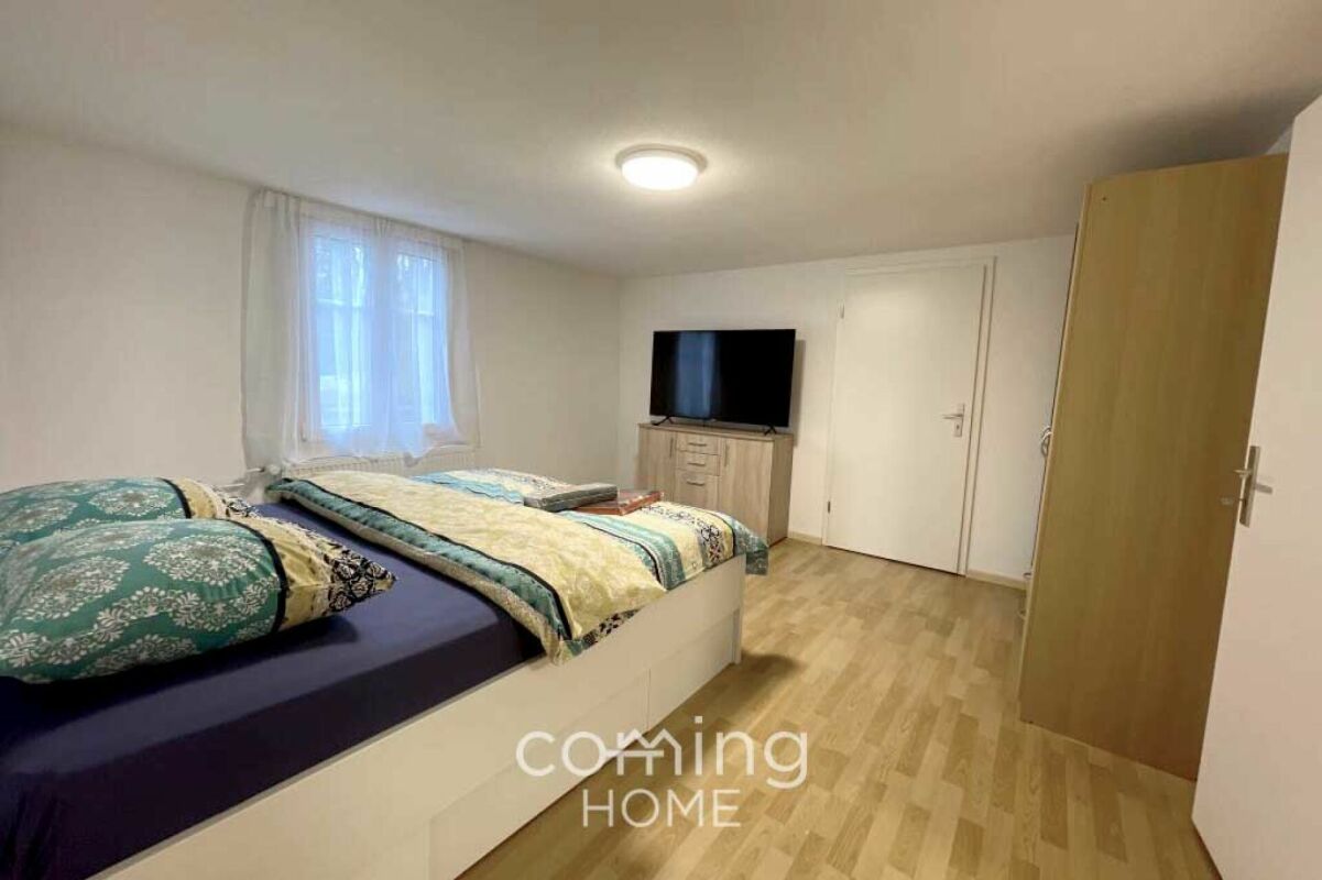 Helles Schlafzimmer mit Doppelbett und TV