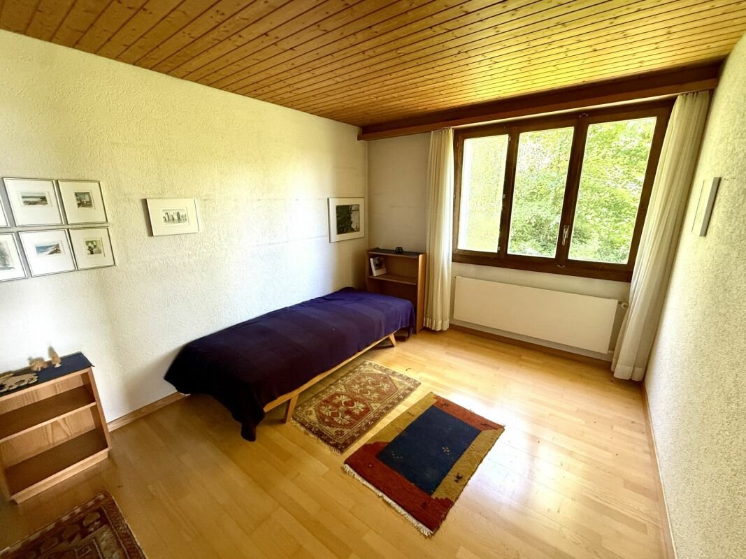Schlichtes Schlafzimmer mit Holzboden und Naturblick