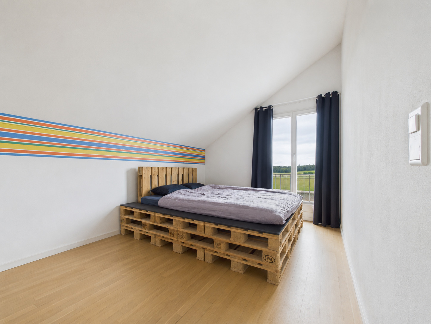 Schlafzimmer mit Palettenbett und Dachschräge
