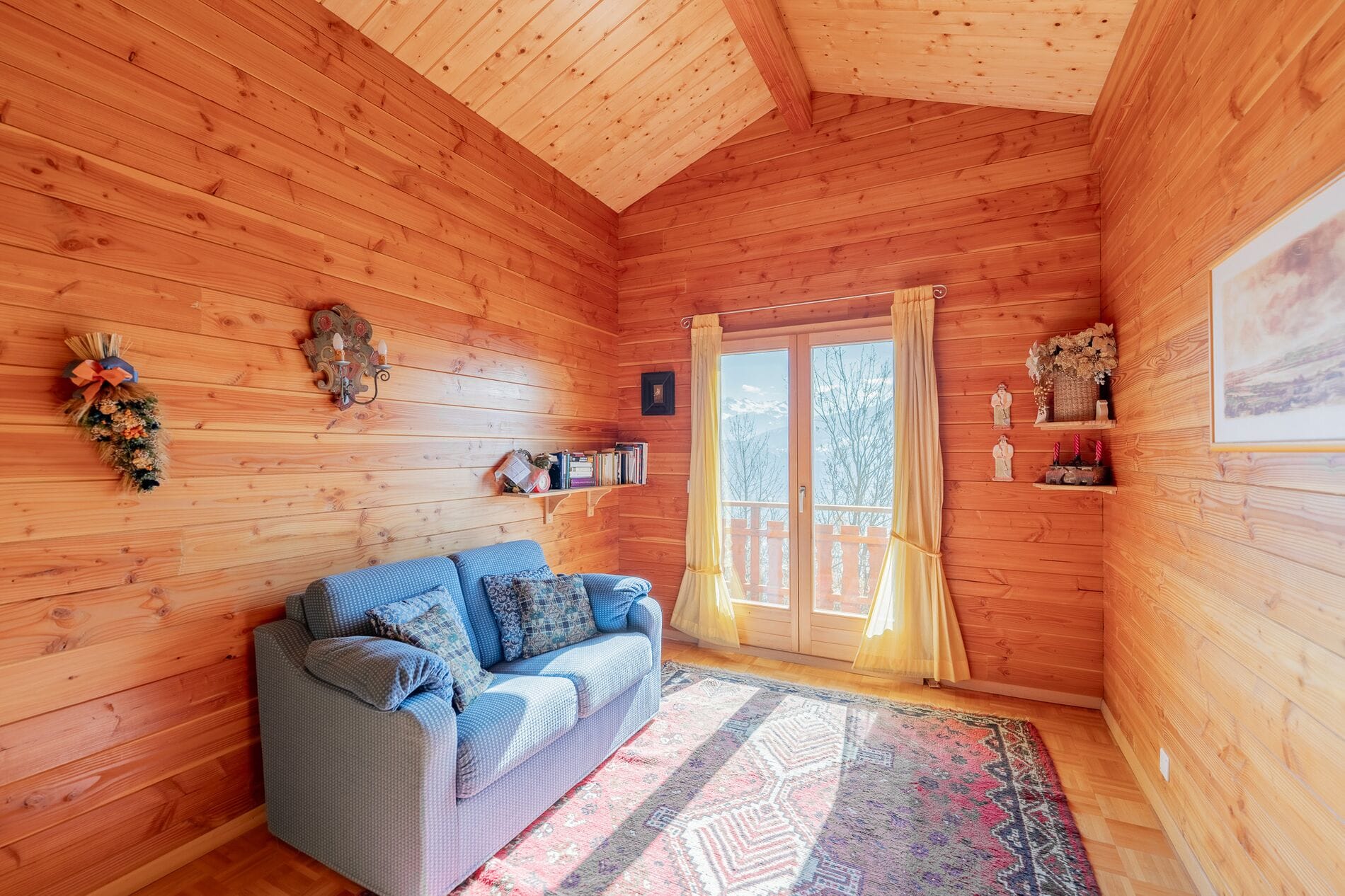 Gemütliches Holzzimmer mit Sofa und Balkonblick