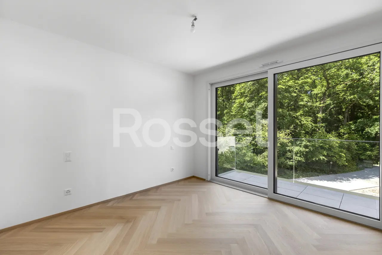 Leerer, heller Raum mit großer Fensterfront zum Grünen