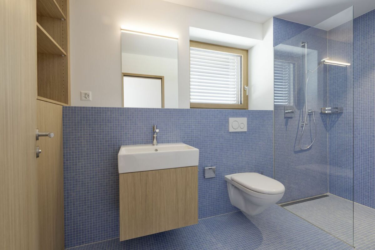 Modernes Badezimmer mit blauem Mosaik und Glasdusche