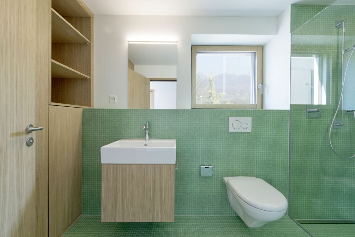 Modernes Bad mit grünem Mosaik und Holzwaschtisch