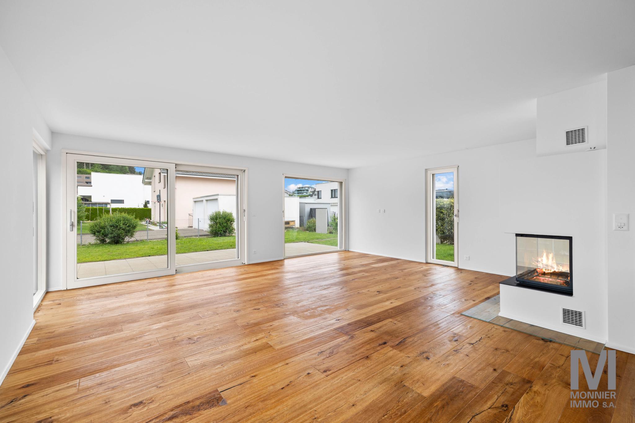 Heller Wohnraum mit Kamin und großen Gartenfenstern