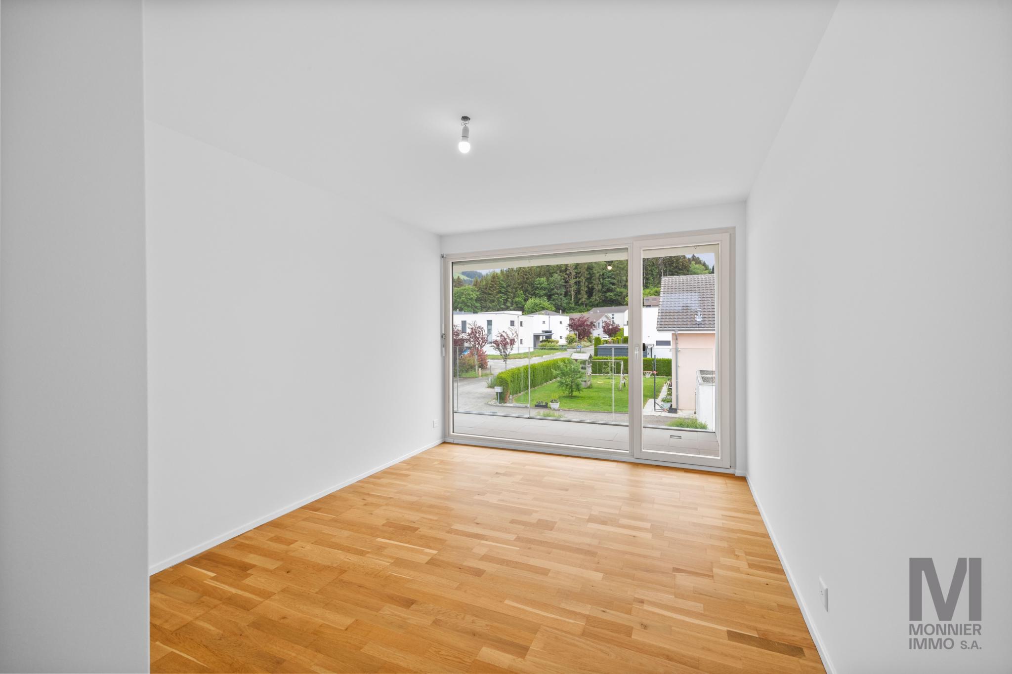 Heller leerer Raum mit Balkonfenster und Blick ins Grüne