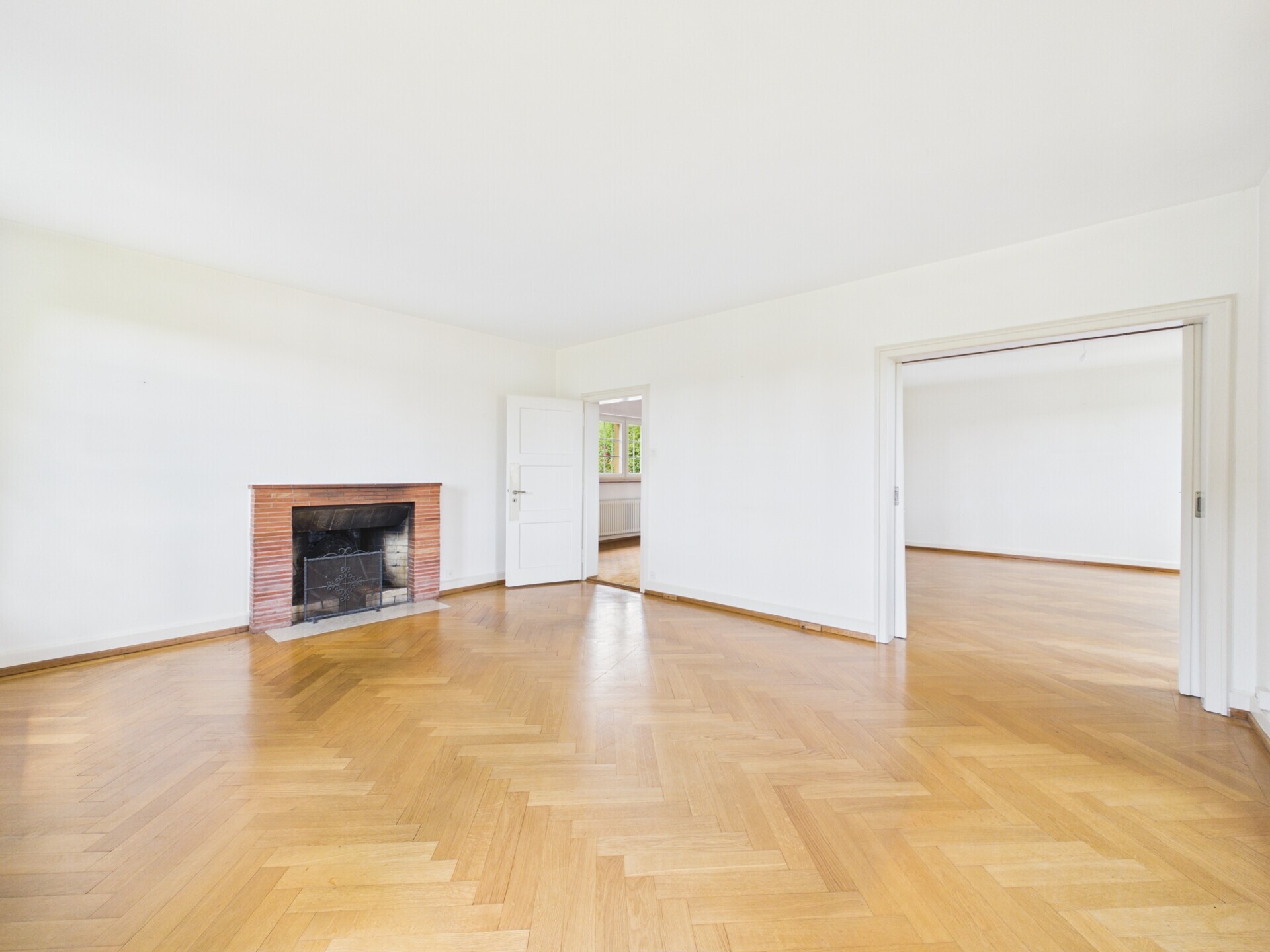 Heller leerer Wohnraum mit Kamin und Parkettboden