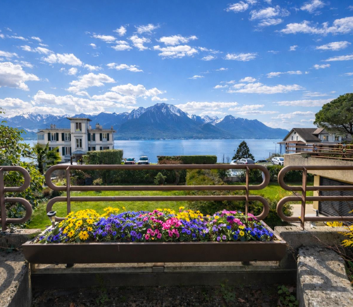 Seeblick mit Bergen und Balkonblumen
