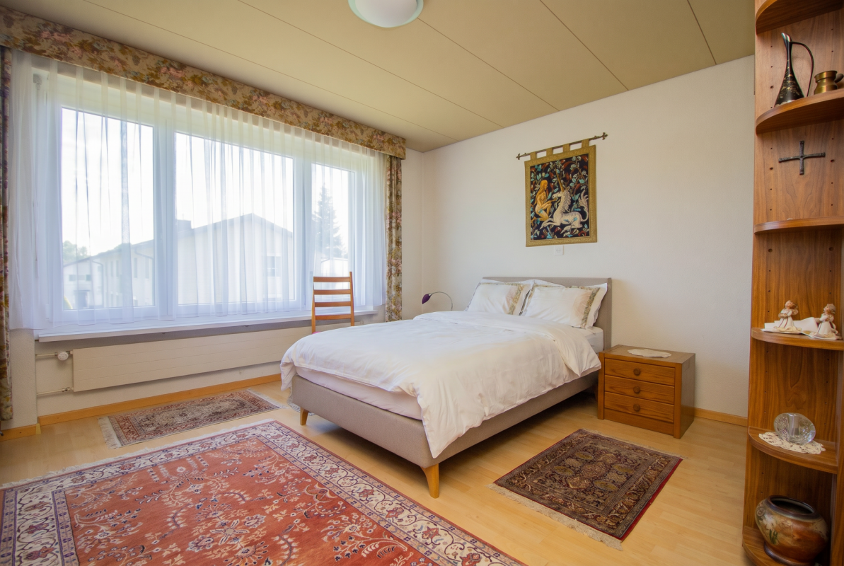 Helles Schlafzimmer mit großem Fenster und Doppelbett