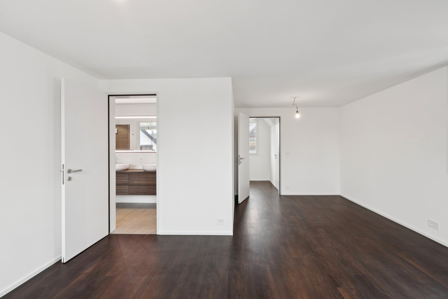 Leerer, modern renovierter Wohnraum mit Blick in angrenzende Räume