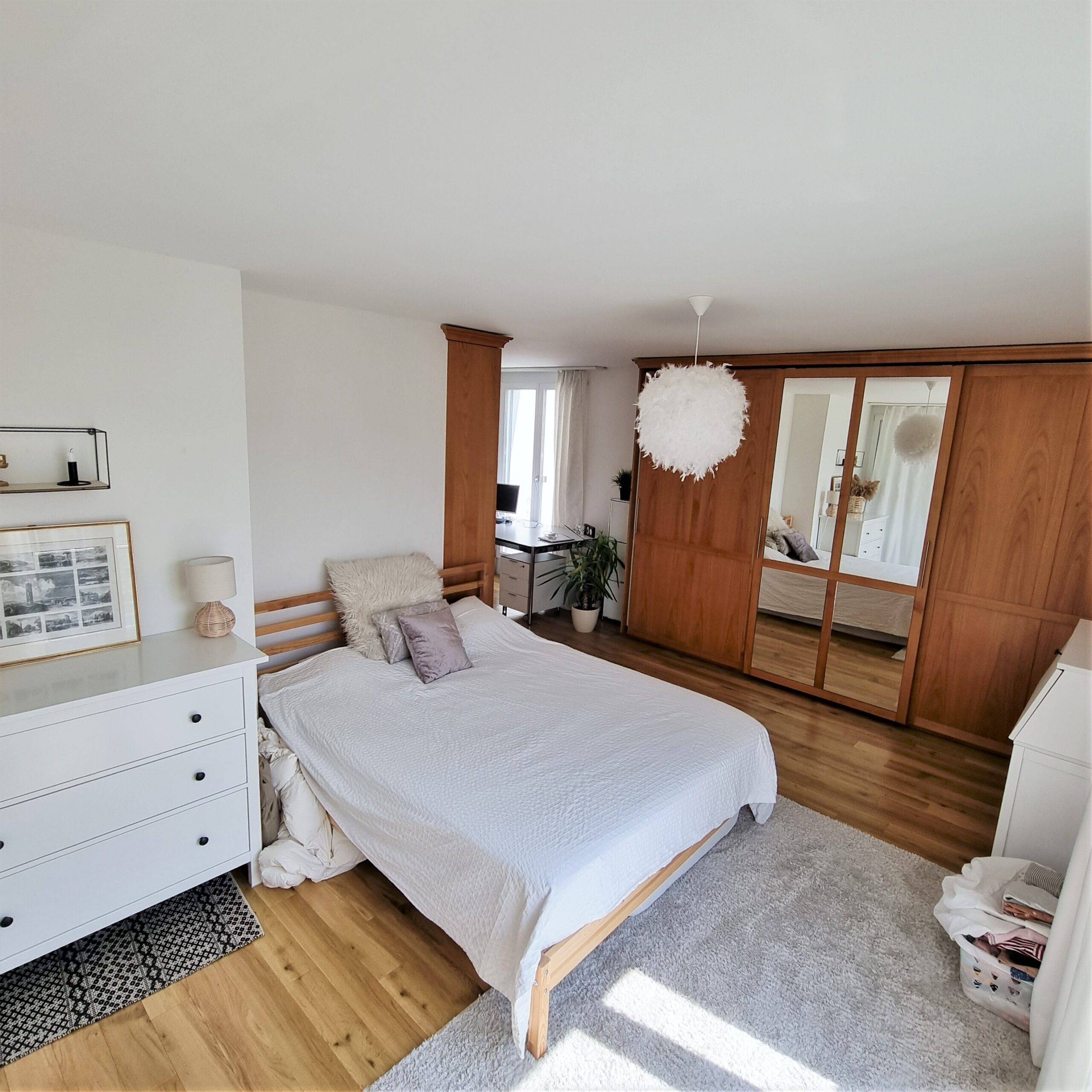 Helles, modern eingerichtetes Schlafzimmer mit Holzschrankwand